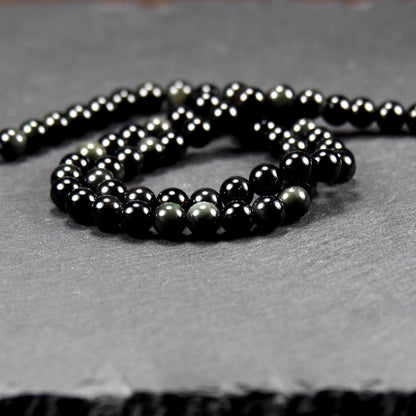 Aufgereihter Perlenstrang aus tiefschwarzen, hochglänzend-polierten, kugelförmigen Obsidianperlen mit glatter Oberfläche.