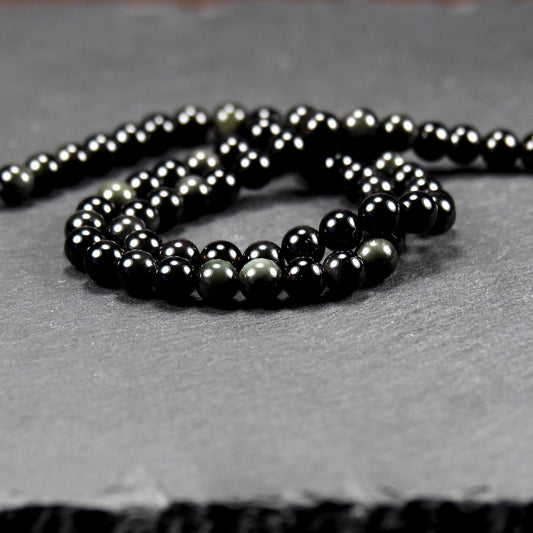 Aufgereihter Perlenstrang aus tiefschwarzen, hochglänzend-polierten, kugelförmigen Obsidianperlen mit glatter Oberfläche.