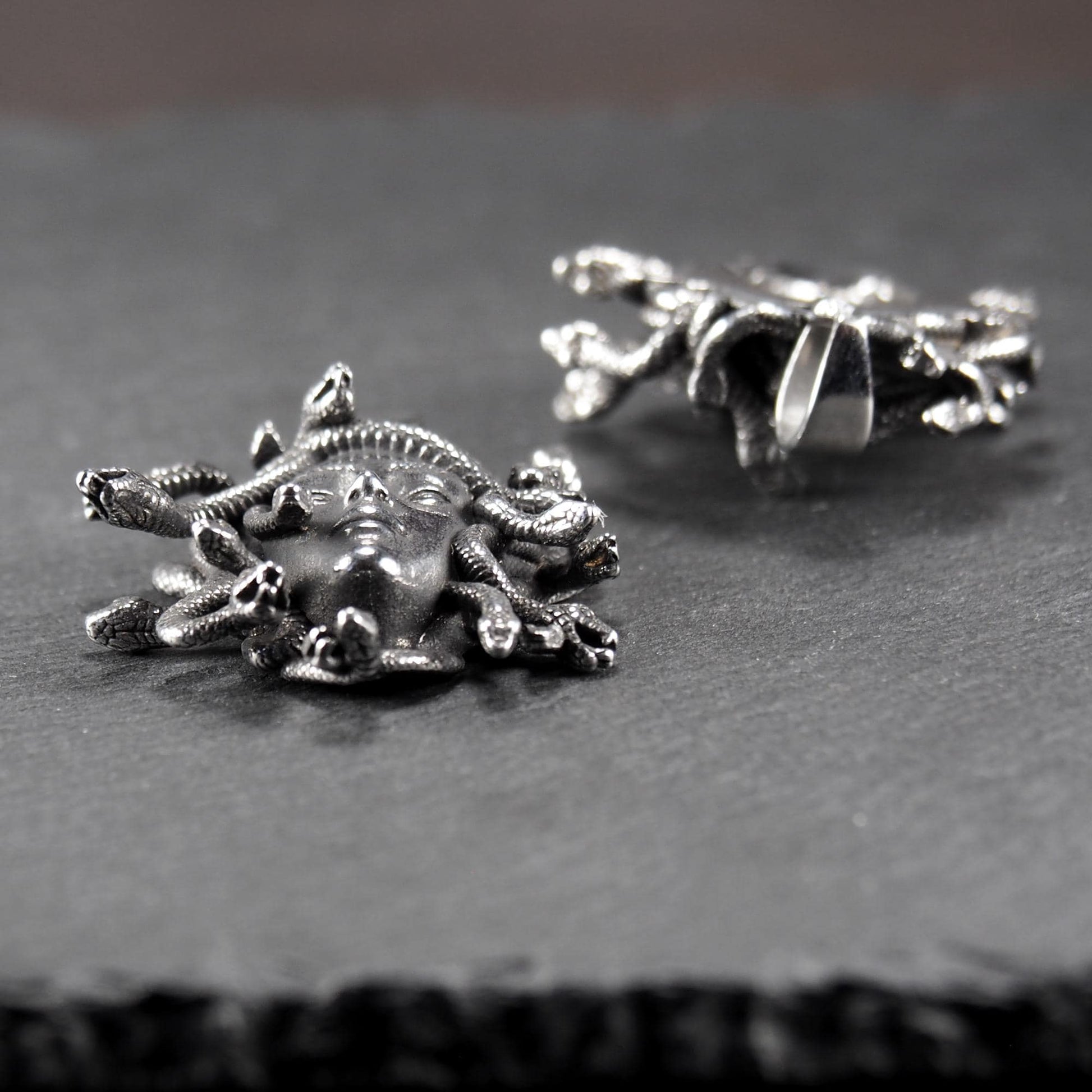 Silberfarbener, dreidimensionaler und glänzender Medusa-Anhänger in Relief mit menschlichem Gesicht und vielen schlangenförmigen Haaren, sichtbarer Öse.