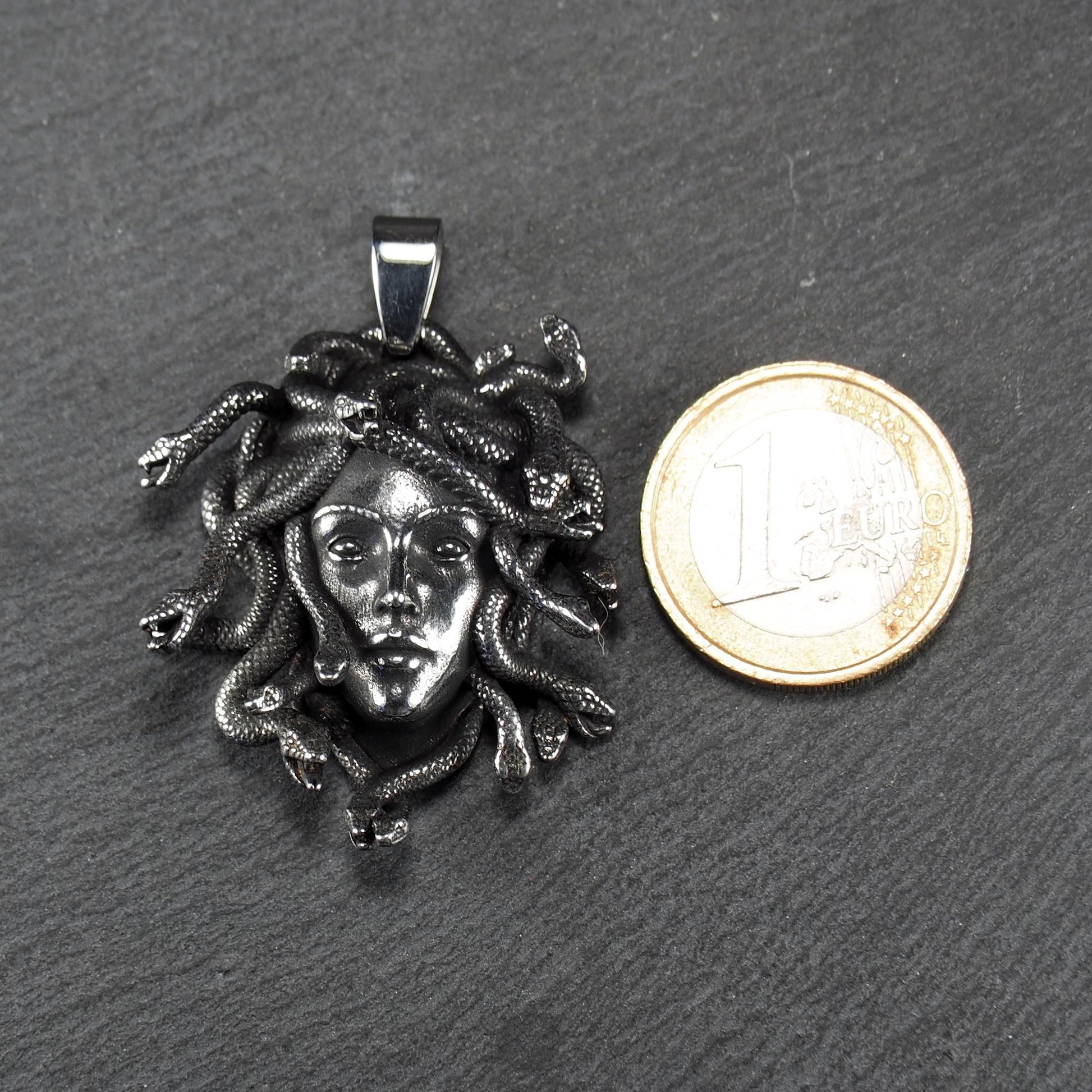 Silberfarbener, dreidimensionaler und glänzender Medusa-Anhänger in Relief mit menschlichem Gesicht und vielen schlangenförmigen Haaren, sichtbarer Öse.