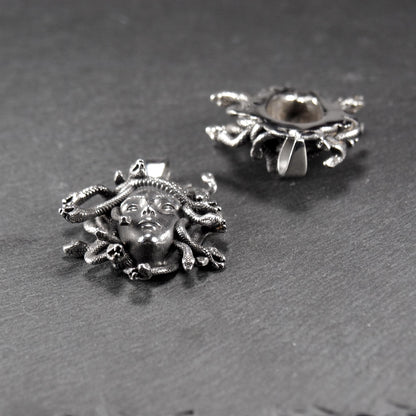 Silberfarbener, dreidimensionaler und glänzender Medusa-Anhänger in Relief mit menschlichem Gesicht und vielen schlangenförmigen Haaren, sichtbarer Öse.