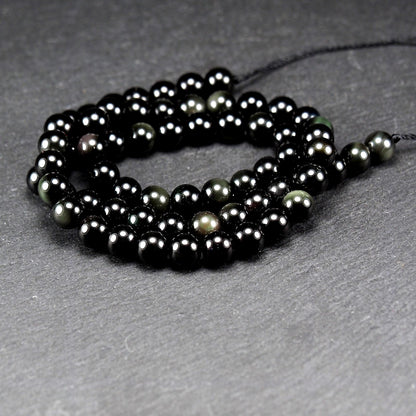Aufgereihter Perlenstrang aus tiefschwarzen, hochglänzend-polierten, kugelförmigen Obsidianperlen mit glatter Oberfläche.