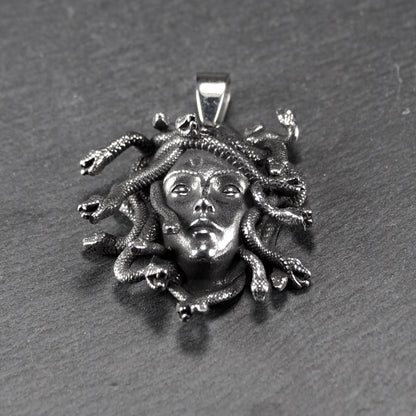 Silberfarbener, dreidimensionaler und glänzender Medusa-Anhänger in Relief mit menschlichem Gesicht und vielen schlangenförmigen Haaren, sichtbarer Öse.