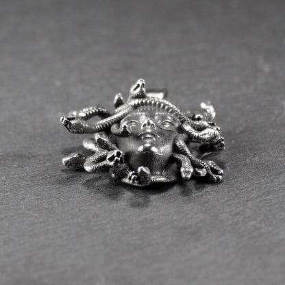 Silberfarbener, dreidimensionaler und glänzender Medusa-Anhänger in Relief mit menschlichem Gesicht und vielen schlangenförmigen Haaren, sichtbarer Öse.