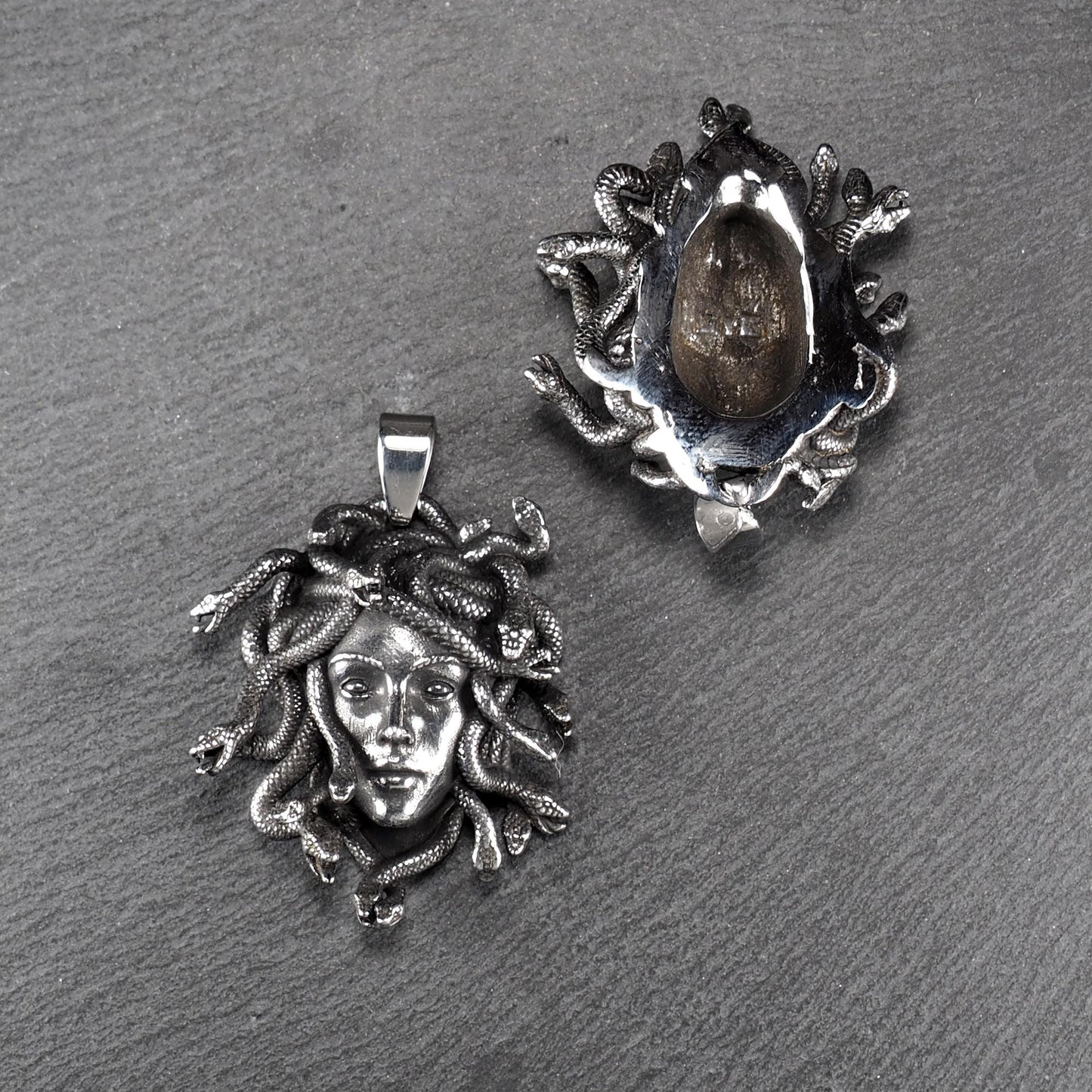 Silberfarbener, dreidimensionaler und glänzender Medusa-Anhänger in Relief mit menschlichem Gesicht und vielen schlangenförmigen Haaren, sichtbarer Öse.