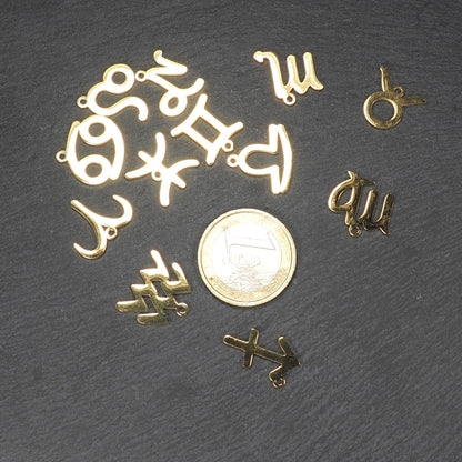 Mehrere flache, goldfarbene, glänzende Anhänger in durchbrochenen Tierkreiszeichenformen mit kleinen Ösen, neben einer 1-Euro-Münze.