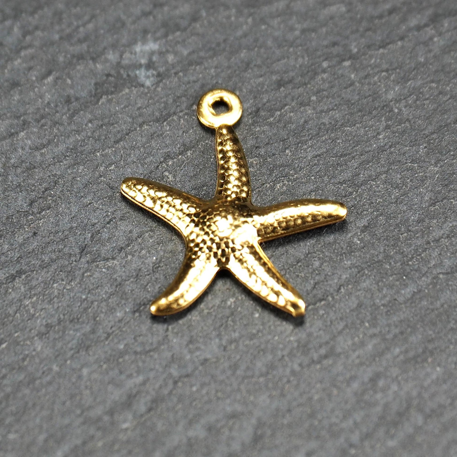 Seestern-Anhänger, goldfarbene glänzende Metalloberfläche mit reliefartiger punktierter Struktur, flach, fünfarmig, oben angegossene runde Öse.