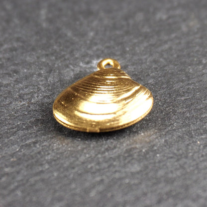 Kleiner muschelförmiger Anhänger, goldfarbene glänzende Oberfläche mit konzentrischen Rillen und integrierter Öse oben.