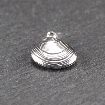 Muschelförmiger silberfarbener Anhänger mit polierter, glänzender Oberfläche, konzentrisch geriffelten Rillen und integrierter runder Öse oben.