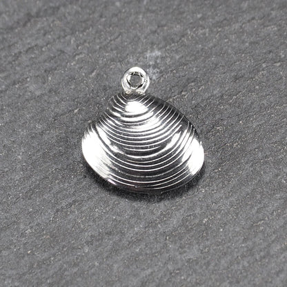 Muschelförmiger silberfarbener Anhänger mit polierter, glänzender Oberfläche, konzentrisch geriffelten Rillen und integrierter runder Öse oben.