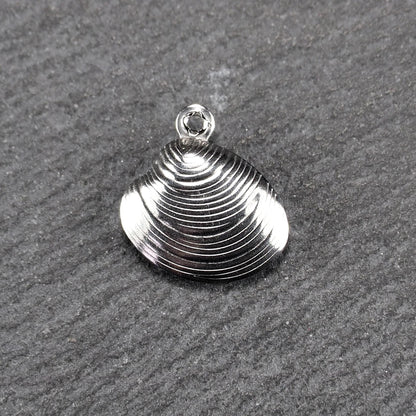 Muschelförmiger silberfarbener Anhänger mit polierter, glänzender Oberfläche, konzentrisch geriffelten Rillen und integrierter runder Öse oben.