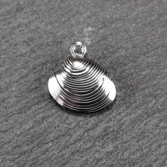 Muschelförmiger silberfarbener Anhänger mit polierter, glänzender Oberfläche, konzentrisch geriffelten Rillen und integrierter runder Öse oben.