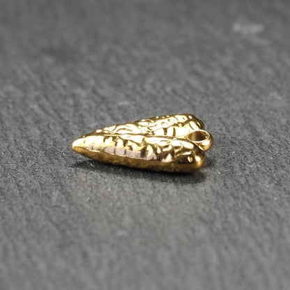 Herzförmiger, vergoldeter Anhänger mit strukturierter Reliefoberfläche, spitz zulaufender Form und integrierter Öse oben.