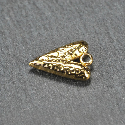 Herzförmiger, vergoldeter Anhänger mit strukturierter Reliefoberfläche, spitz zulaufender Form und integrierter Öse oben.