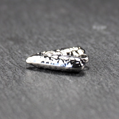 Herzanhänger, silberfarbig hochglänzend mit reliefartiger Oberfläche, spitz zulaufender Unterseite und integrierter runder Öse.