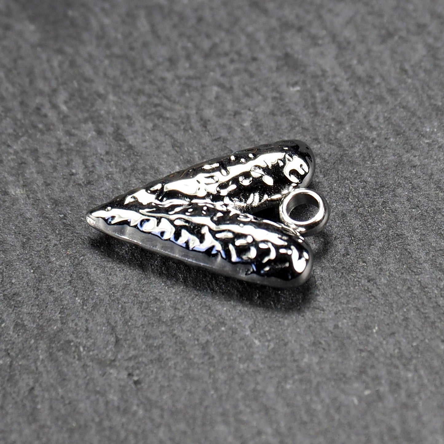 Herzanhänger, silberfarbig hochglänzend mit reliefartiger Oberfläche, spitz zulaufender Unterseite und integrierter runder Öse.