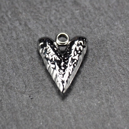 Herzanhänger, silberfarbig hochglänzend mit reliefartiger Oberfläche, spitz zulaufender Unterseite und integrierter runder Öse.
