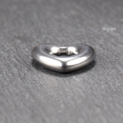 Herzanhänger, glänzend poliertes silbernes Metall mit rundem, durchbrochenem Innenfeld und glatten, abgerundeten Kanten auf dunklem Hintergrund.