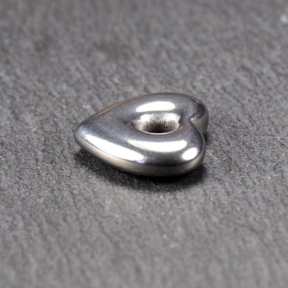 Herzförmiger, silberfarben glänzender Metallanhänger mit glatter Oberfläche und mittigem rundem Fädelloch.