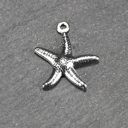 Seestern-Anhänger aus silberfarbenem Metall mit reliefartiger, strukturierter glänzender Oberfläche, fünf Armen und kleiner runder Öse oben.