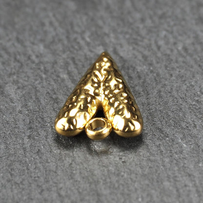 Herzförmiger, vergoldeter Anhänger mit strukturierter Reliefoberfläche, spitz zulaufender Form und integrierter Öse oben.