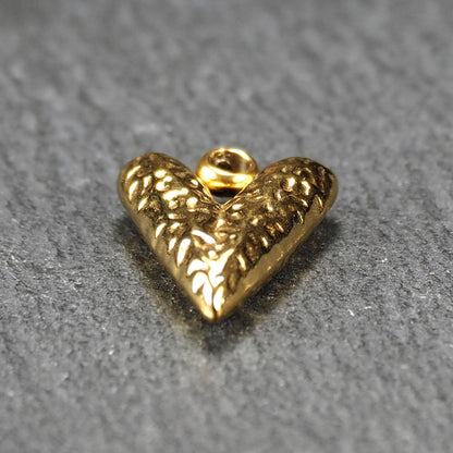 Herzförmiger, vergoldeter Anhänger mit strukturierter Reliefoberfläche, spitz zulaufender Form und integrierter Öse oben.