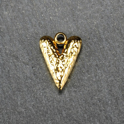 Herzförmiger, vergoldeter Anhänger mit strukturierter Reliefoberfläche, spitz zulaufender Form und integrierter Öse oben.