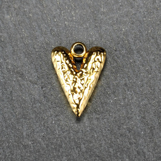 Herzförmiger, vergoldeter Anhänger mit strukturierter Reliefoberfläche, spitz zulaufender Form und integrierter Öse oben.