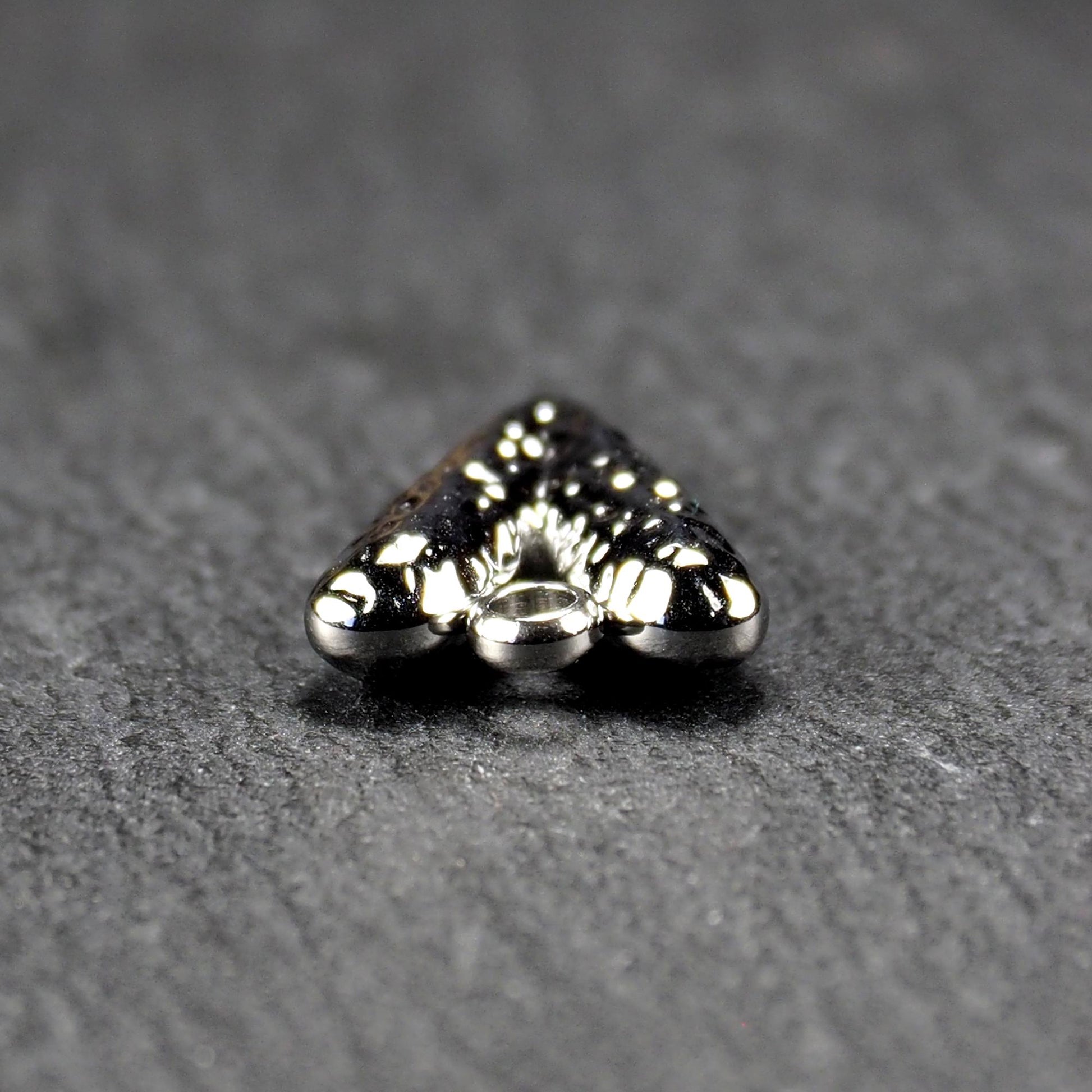 Herzanhänger, silberfarbig hochglänzend mit reliefartiger Oberfläche, spitz zulaufender Unterseite und integrierter runder Öse.