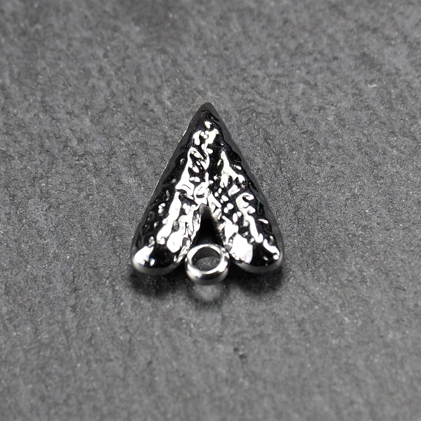 Herzanhänger, silberfarbig hochglänzend mit reliefartiger Oberfläche, spitz zulaufender Unterseite und integrierter runder Öse.