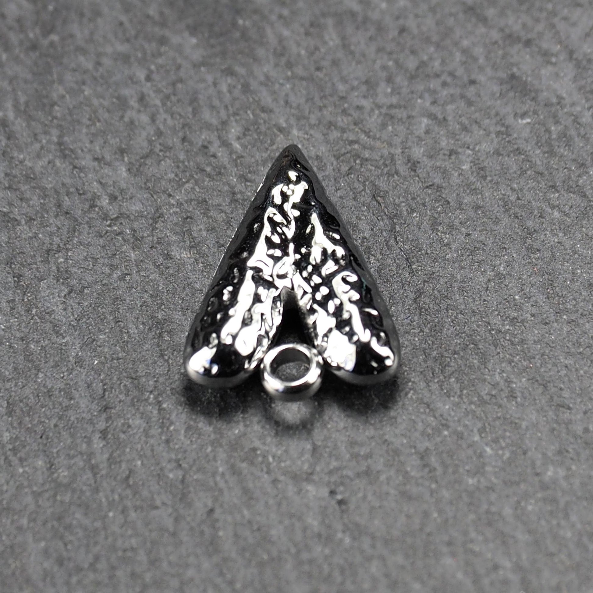 Herzanhänger, silberfarbig hochglänzend mit reliefartiger Oberfläche, spitz zulaufender Unterseite und integrierter runder Öse.