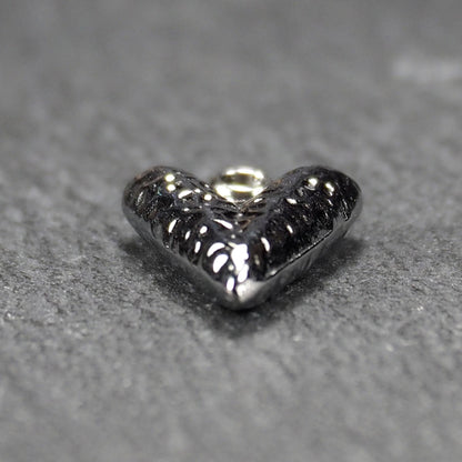 Herzanhänger, silberfarbig hochglänzend mit reliefartiger Oberfläche, spitz zulaufender Unterseite und integrierter runder Öse.