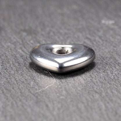 Herzförmiger, silberfarben glänzender Metallanhänger mit glatter Oberfläche und mittigem rundem Fädelloch.