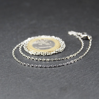 Eine Ankerkette hat filigrane offene Ankerglieder, polierte silberne Oberfläche und einen sichtbaren Karabinerverschluss.