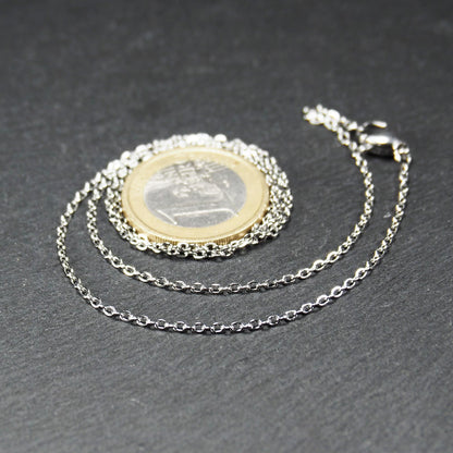 Eine Ankerkette hat filigrane offene Ankerglieder, polierte silberne Oberfläche und einen sichtbaren Karabinerverschluss.