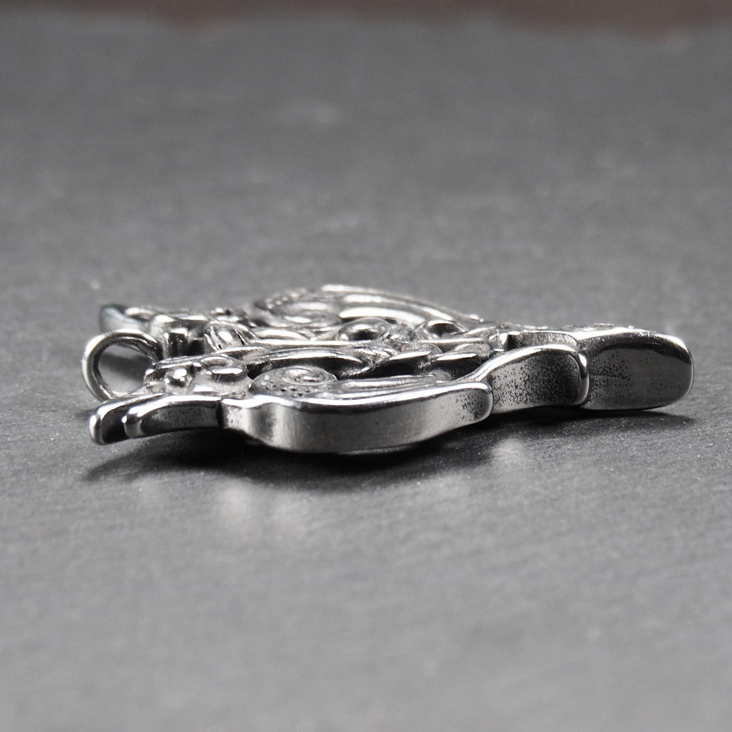 Anhänger aus poliertem silberfarbenem Edelstahl, zweiköpfiges, spitz zulaufendes Rabenschwert Ornament mit Relief, Durchbrüchen und sichtbarer Öse.