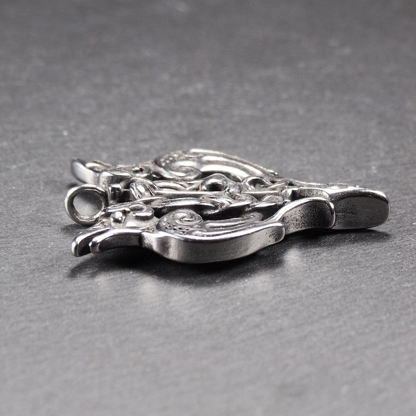 Anhänger aus poliertem silberfarbenem Edelstahl, zweiköpfiges, spitz zulaufendes Rabenschwert Ornament mit Relief, Durchbrüchen und sichtbarer Öse.