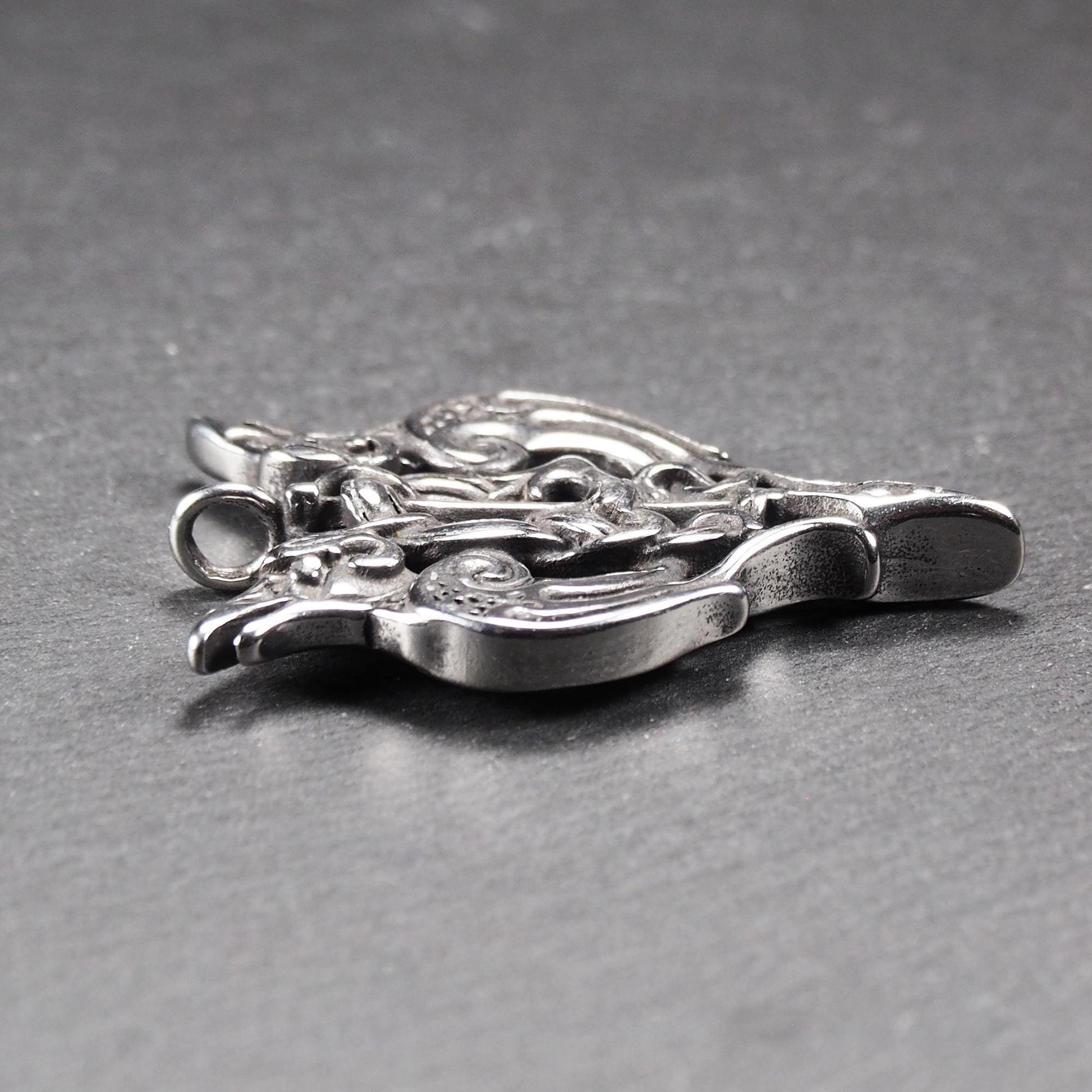 Anhänger aus poliertem silberfarbenem Edelstahl, zweiköpfiges, spitz zulaufendes Rabenschwert Ornament mit Relief, Durchbrüchen und sichtbarer Öse.