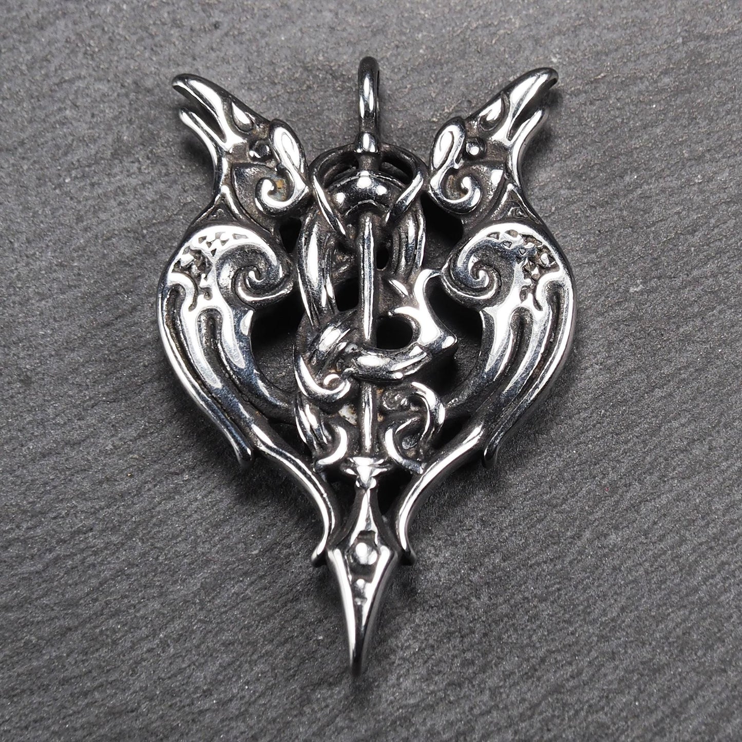 Anhänger aus poliertem silberfarbenem Edelstahl, zweiköpfiges, spitz zulaufendes Rabenschwert Ornament mit Relief, Durchbrüchen und sichtbarer Öse.