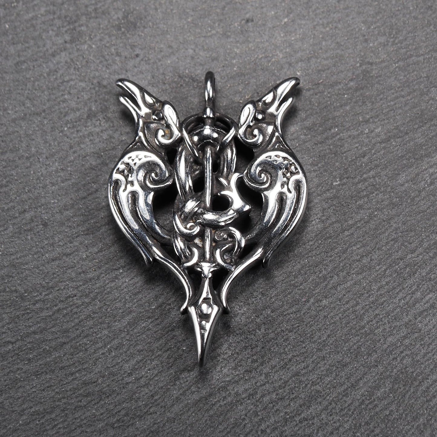 Anhänger aus poliertem silberfarbenem Edelstahl, zweiköpfiges, spitz zulaufendes Rabenschwert Ornament mit Relief, Durchbrüchen und sichtbarer Öse.