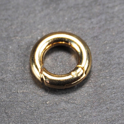 Runder vergoldeter O-Ring Karabiner mit glänzender Oberfläche, torusförmiger Öffnung und sichtbarem Schnappverschluss mit Scharnier.
