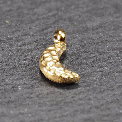 Halbmond-Anhänger, goldfarben und glänzend, reliefartige gehämmerte Textur, organisch geschwungene Mondsichelform mit kleiner Öse oben.