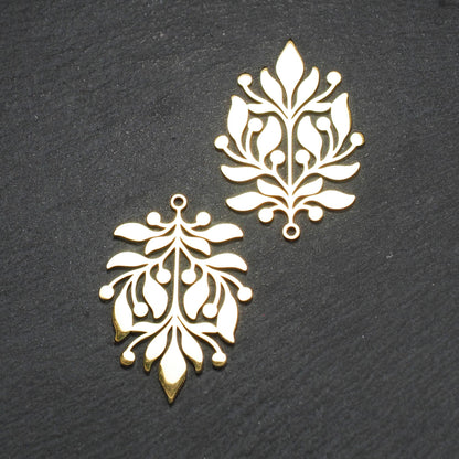 Goldfarbener Metallanhänger mit glänzender Oberfläche, durchbrochenes Zweig- und Beerenmotiv mit stilisierten Blättern und runder Öse oben.