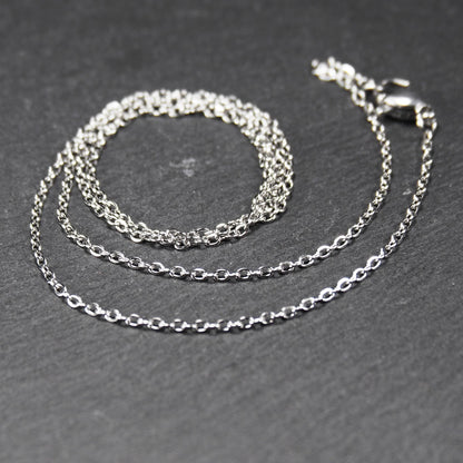 Eine Ankerkette hat filigrane offene Ankerglieder, polierte silberne Oberfläche und einen sichtbaren Karabinerverschluss.