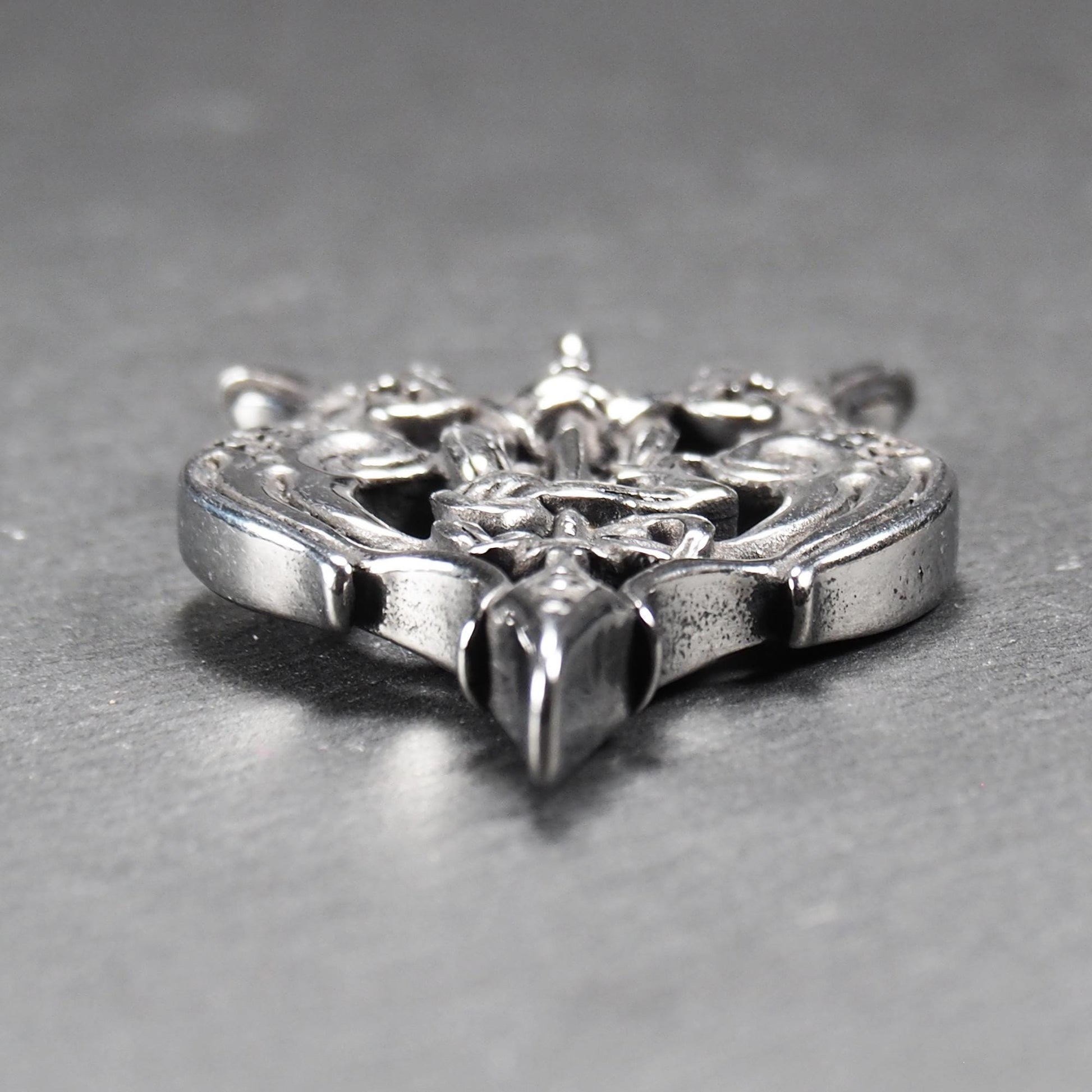 Anhänger aus poliertem silberfarbenem Edelstahl, zweiköpfiges, spitz zulaufendes Rabenschwert Ornament mit Relief, Durchbrüchen und sichtbarer Öse.