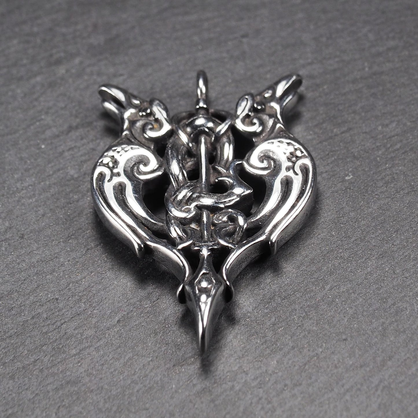 Anhänger aus poliertem silberfarbenem Edelstahl, zweiköpfiges, spitz zulaufendes Rabenschwert Ornament mit Relief, Durchbrüchen und sichtbarer Öse.