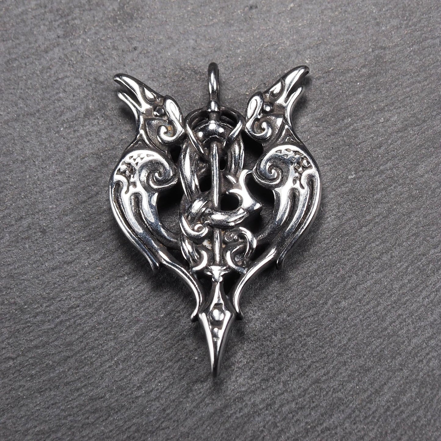 Anhänger aus poliertem silberfarbenem Edelstahl, zweiköpfiges, spitz zulaufendes Rabenschwert Ornament mit Relief, Durchbrüchen und sichtbarer Öse.