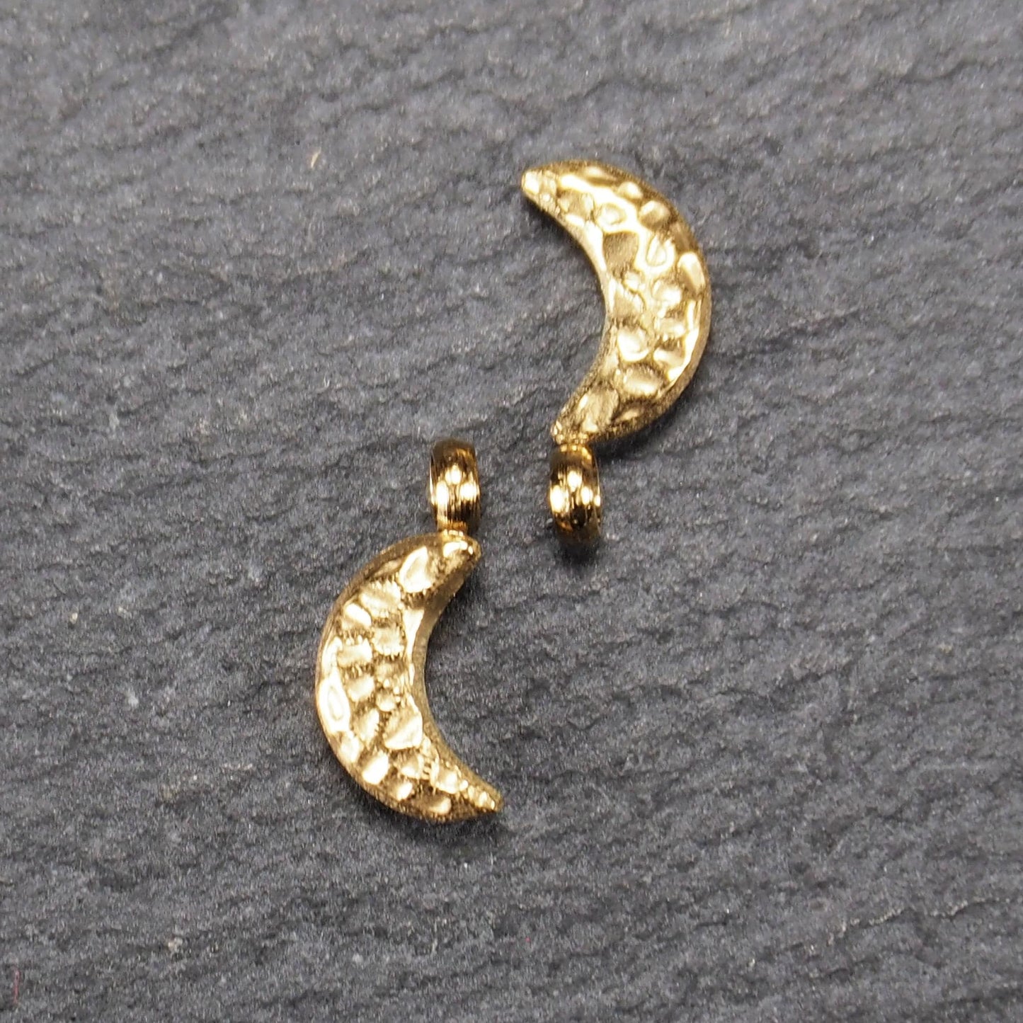 Halbmond-Anhänger, goldfarben und glänzend, reliefartige gehämmerte Textur, organisch geschwungene Mondsichelform mit kleiner Öse oben.