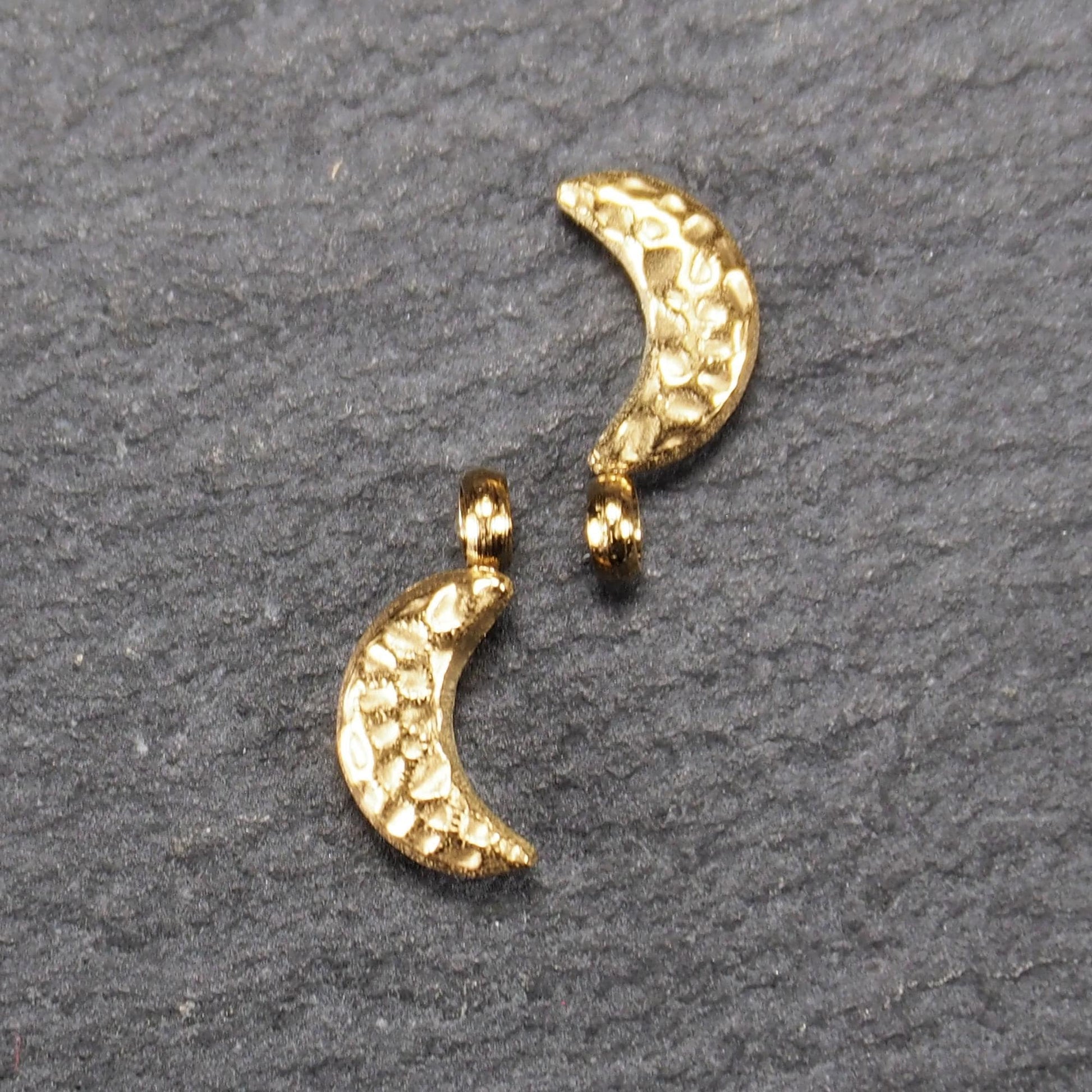 Halbmond-Anhänger, goldfarben und glänzend, reliefartige gehämmerte Textur, organisch geschwungene Mondsichelform mit kleiner Öse oben.