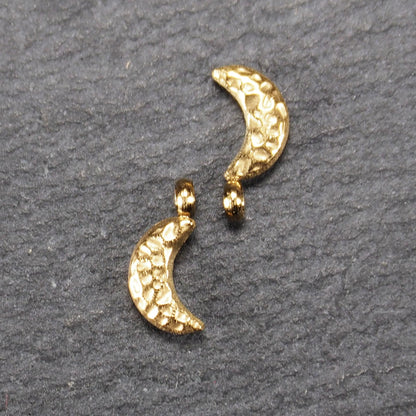 Halbmond-Anhänger, goldfarben und glänzend, reliefartige gehämmerte Textur, organisch geschwungene Mondsichelform mit kleiner Öse oben.